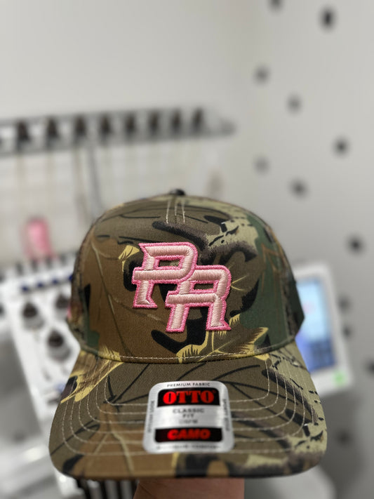 PR (Puerto Rico) embroidered 3D in pink thread on a Otto camo trucker hat.